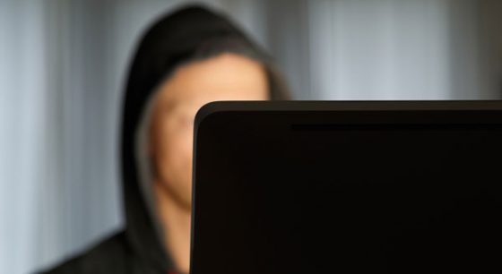 jongen met cap op verscholen achter de computer